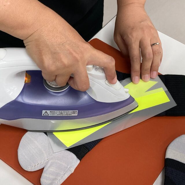 ウルトラアーチのプリントは、日本の工場で職人さんが一足ずつ手作業で仕上げています。
シリコンゴムを後脛骨筋のラインに沿って貼り付け、仮止め → プレス → 本プレスの3工程を丁寧に積み重ねる。
大量生産には向かないかもしれない。
それでも、この“手間”こそが足のポテンシャルを引き出すために欠かせないと感じています。

内側から崩れるように落ちてしまう舟状骨を、真下ではなく内側から支えて引き上げる構造。
フォアフットで踵が上がった状態でも、蹴り出しの最後の最後までアーチを支え続ける。

機能を“盛る”のではなく、
足が本来持つ力を最大化するための、日本の職人技。 
それがウルトラアーチのプリントです。